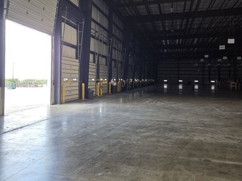 Open drive-in door and dock doors inside the warehouse looking out to the yard