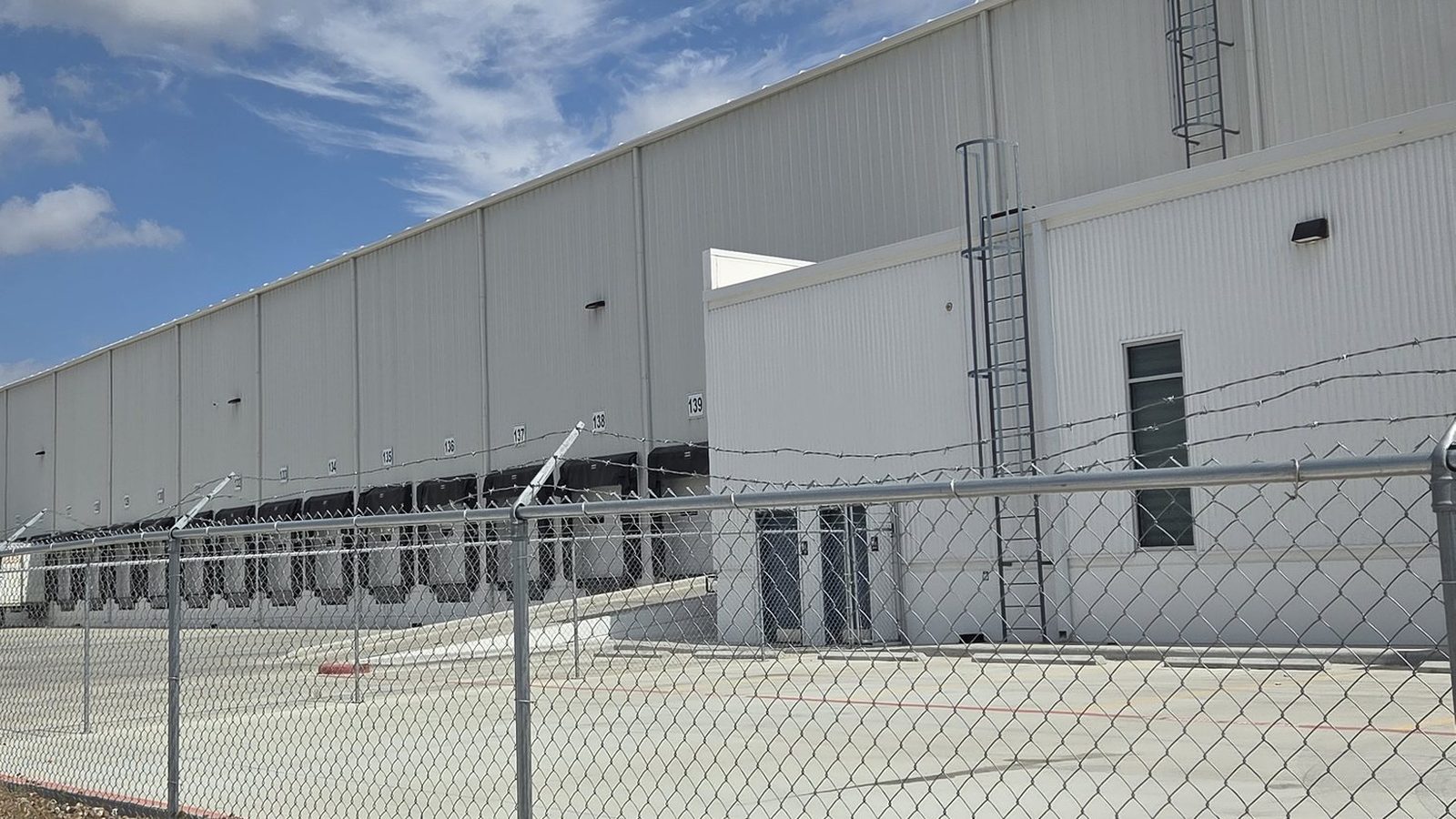 Exterior of the Tetrad Laredo warehouse: a tilt-wall, dock-high facility behind a secured perimeter fence