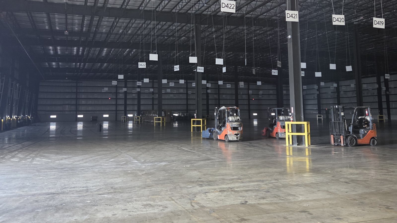 Open, high-clearance warehouse floor with forklifts and numbered dock positions