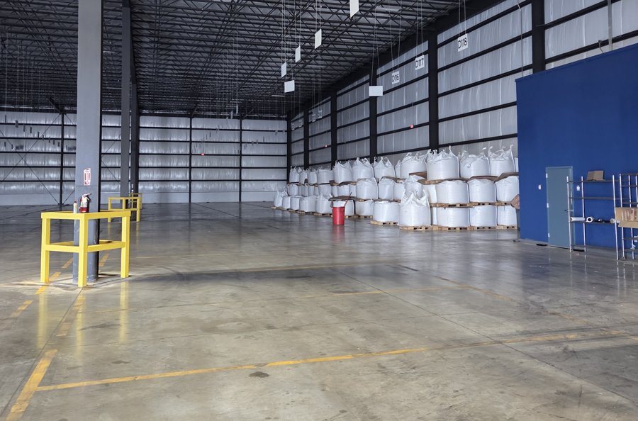 Clean, lit staging space inside the warehouse with palletized material against the wall