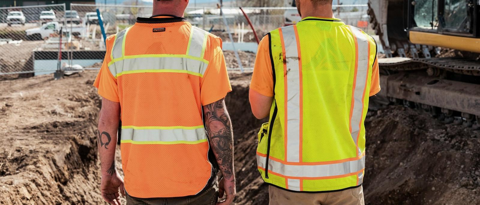 Two site personnel in high-visibility clothing reviewing works in progress